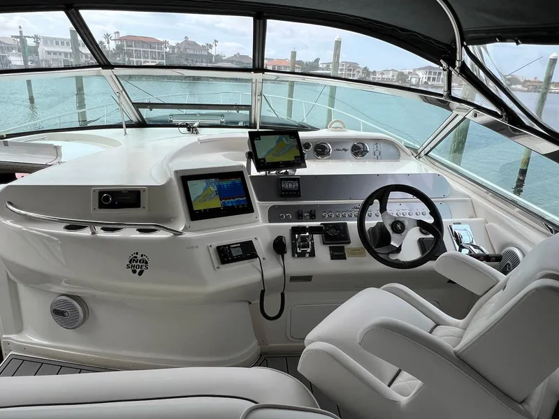 Slide: The Image of 1997 Sea Ray 450 Sundancer helm with navigation screens and steering wheel, docked by the water. - 12