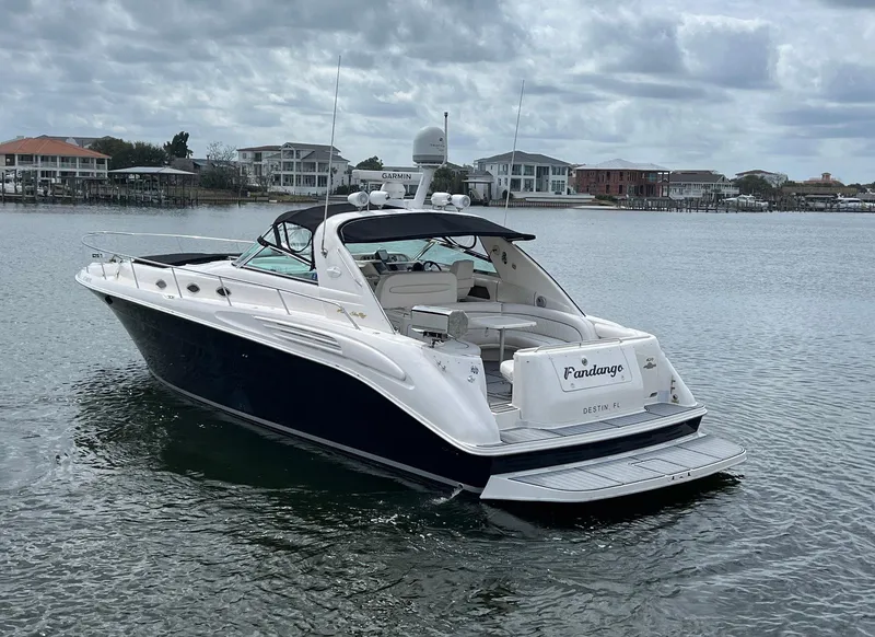 Slide: The Image of 1997 Sea Ray 450 Sundancer yacht on calm water with coastal homes in the background. - 16
