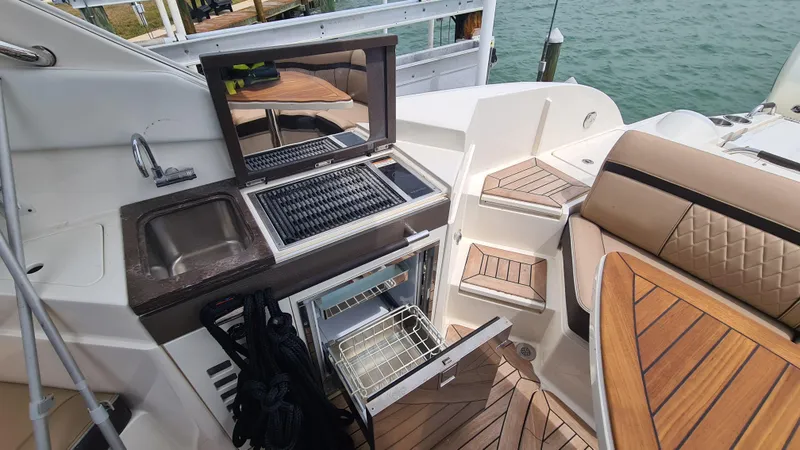 Slide: The Image of 2017 Sea Ray SLX 350 OB boat interior with kitchenette and seating area. - 13