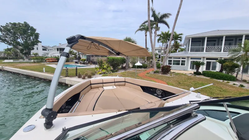 Slide: The Image of 2017 Sea Ray SLX 350 OB boat docked near waterfront homes, featuring a sunshade and spacious seating. - 6