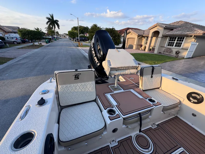 Slide: The Image of 2021 Carolina Skiff Ultra Elite 24 boat interior with seating and motor, parked in a suburban street. - 24