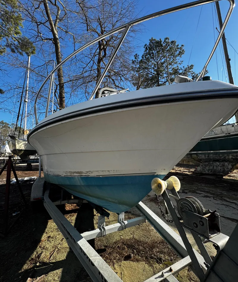 Slide: The Image of 2001 Aquasport 215 Explorer boat on trailer, surrounded by trees under clear blue sky. - 35
