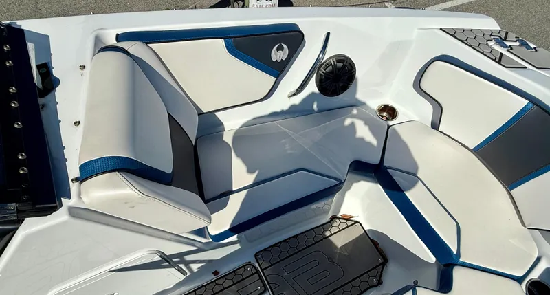 Slide: The Image of 2020 Scarab 215 ID boat interior with white and blue seating, speaker, and storage compartments. - 13