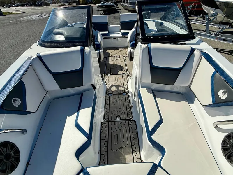 Slide: The Image of 2020 Scarab 215 ID boat interior with white and blue seating, dual windshields, and speakers. - 15