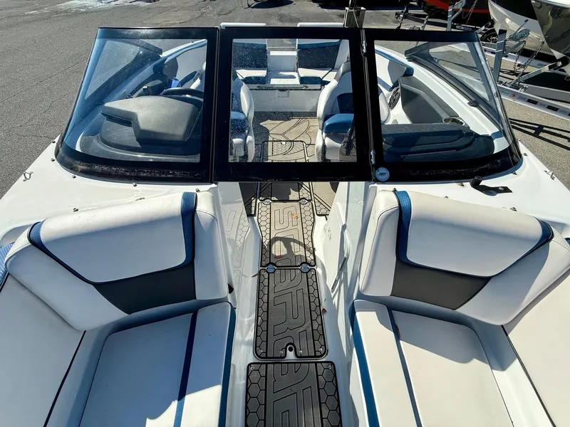 Slide: The Image of 2020 Scarab 215 ID boat interior with white and blue seating, open windshield, and textured flooring. - 16