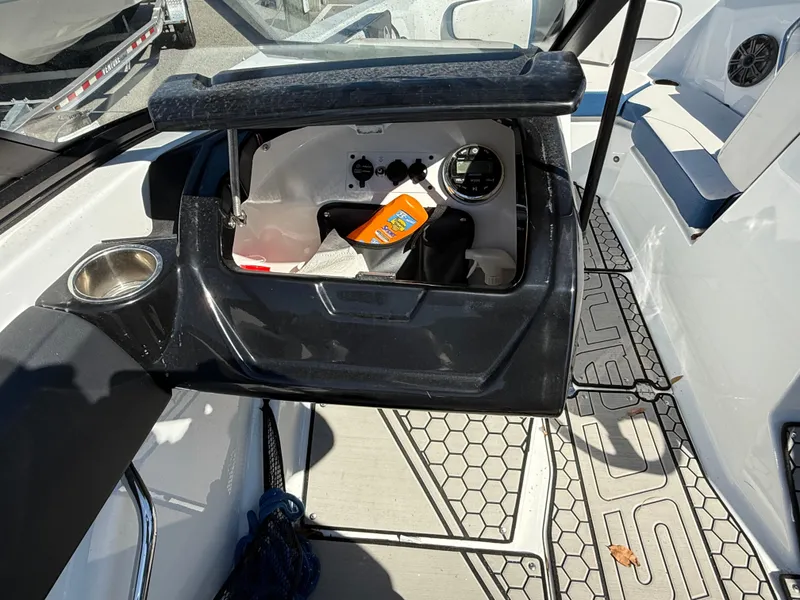 Slide: The Image of 2020 Scarab 215 ID boat interior with open storage compartment and cup holder. - 18