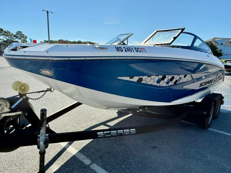 Slide: The Image of 2020 Scarab 215 ID boat on trailer, blue and white design, parked outdoors. - 8