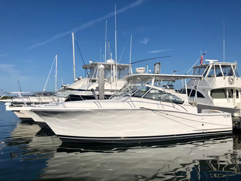Slide: The Image of 2005 Luhrs 30 Hard Top boat docked in a marina under clear blue skies. - 0