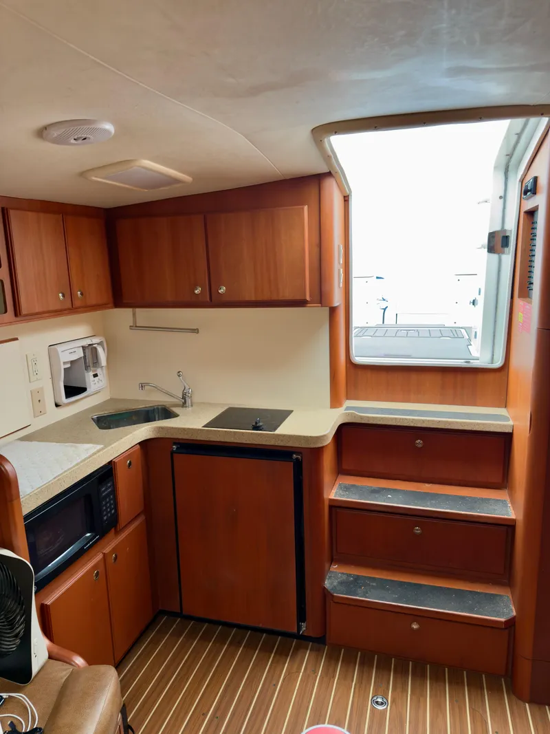 Slide: The Image of 2005 Luhrs 30 Hard Top interior kitchen with wooden cabinets and modern appliances. - 17