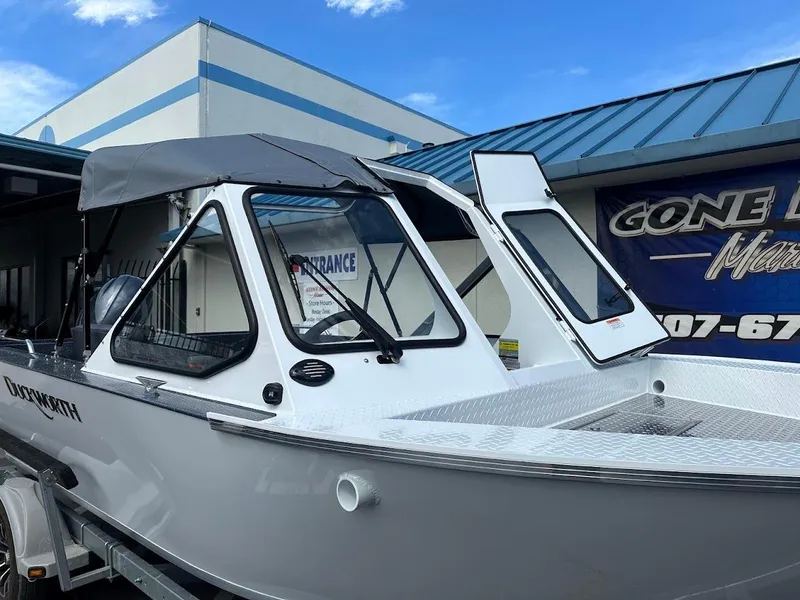 Slide: The Image of 2025 Duckworth 18 Advantage boat with canopy, parked on trailer, outside a marine store. - 7