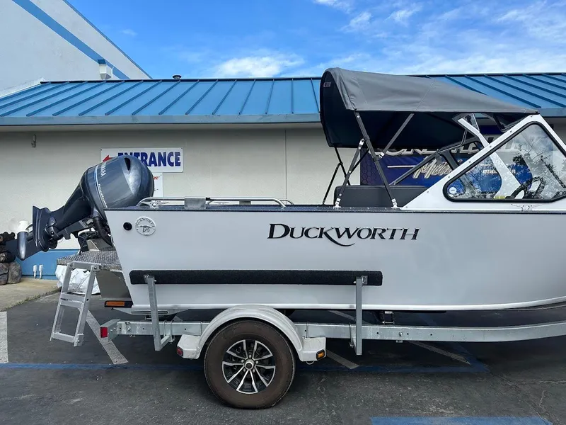 Slide: The Image of 2025 Duckworth 18 Advantage boat with outboard motor, parked on a trailer near a building. - 8