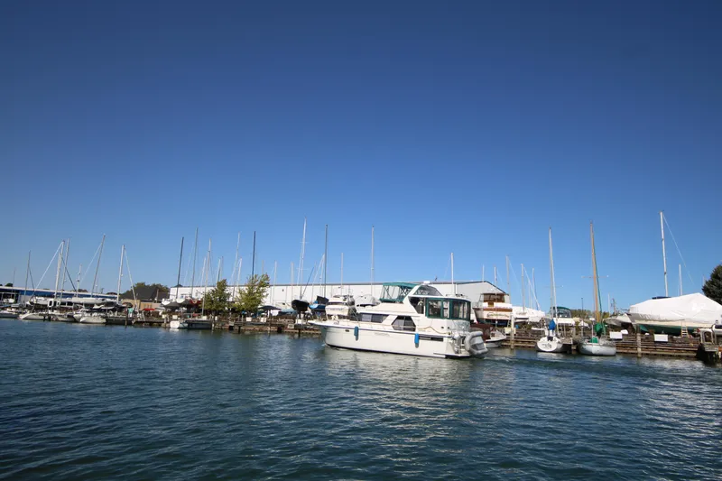 Slide: The Image of 1994 Carver 440 Aft Cabin Motor Yacht docked in a marina under clear blue sky. - 49