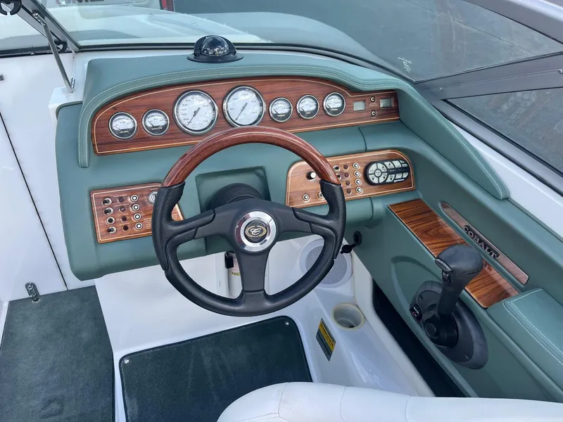 Slide: The Image of 2002 Cobalt 246 boat dashboard with wood accents and steering wheel. - 10