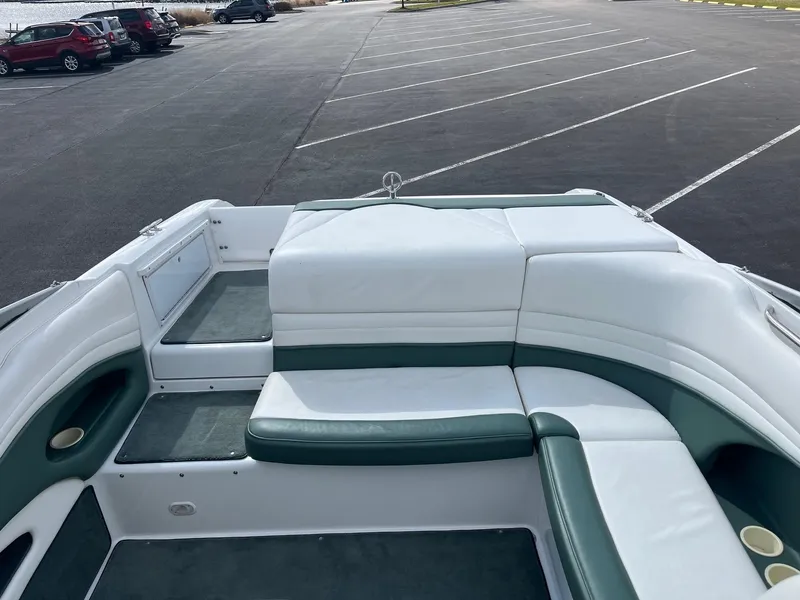 Slide: The Image of 2002 Cobalt 246 boat interior with white and green seating in an empty parking lot. - 14