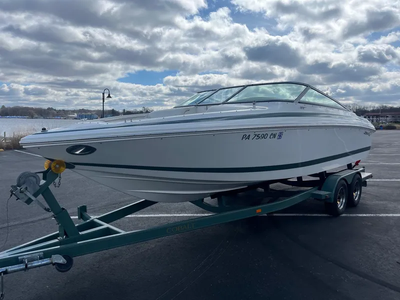 Slide: The Image of 2002 Cobalt 246 boat on trailer under cloudy sky. - 2