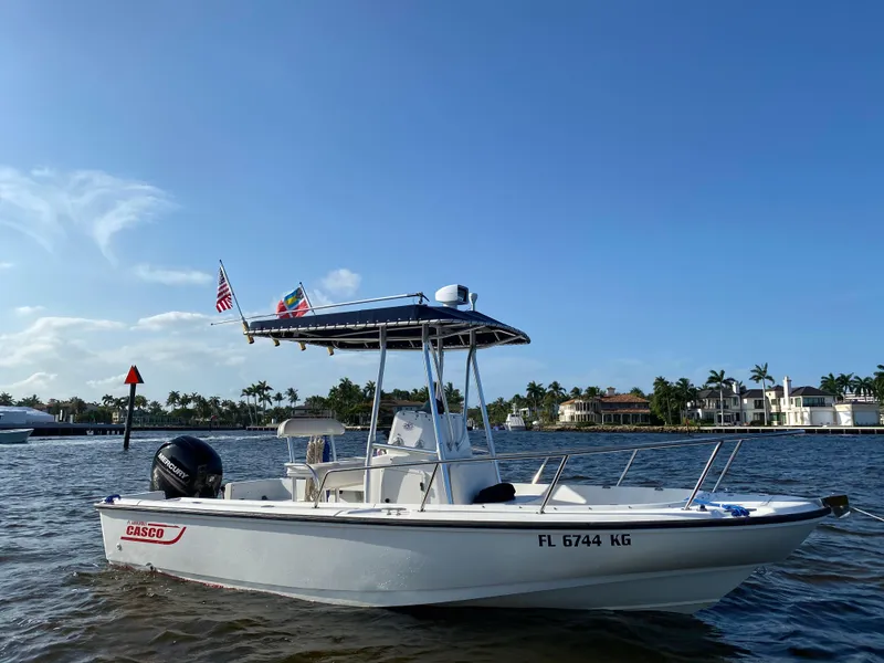 Slide: The Image of 1998 Boston Whaler Outrage 20 boat on water, clear sky, waterfront homes in background. - 1