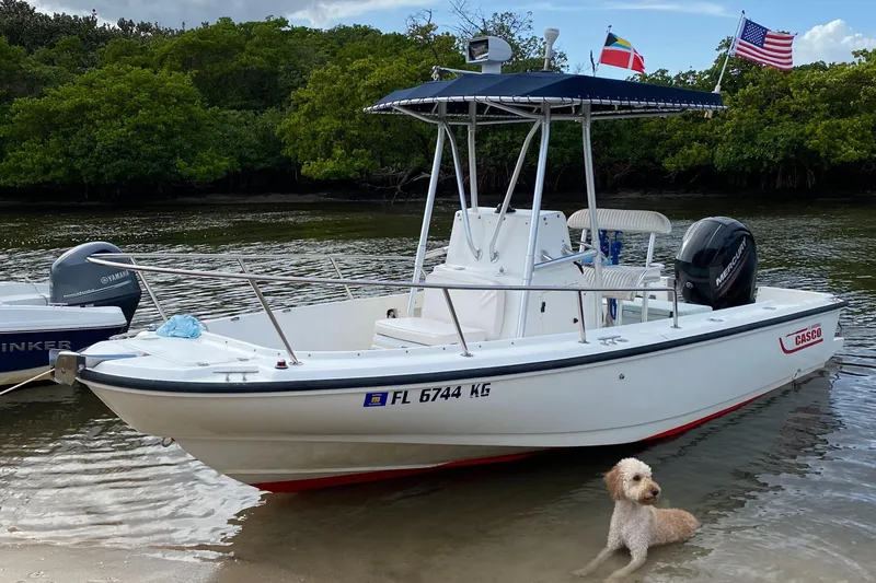 Slide: The Image of 1998 Boston Whaler Outrage 20 boat docked on shore with a dog nearby. - 7