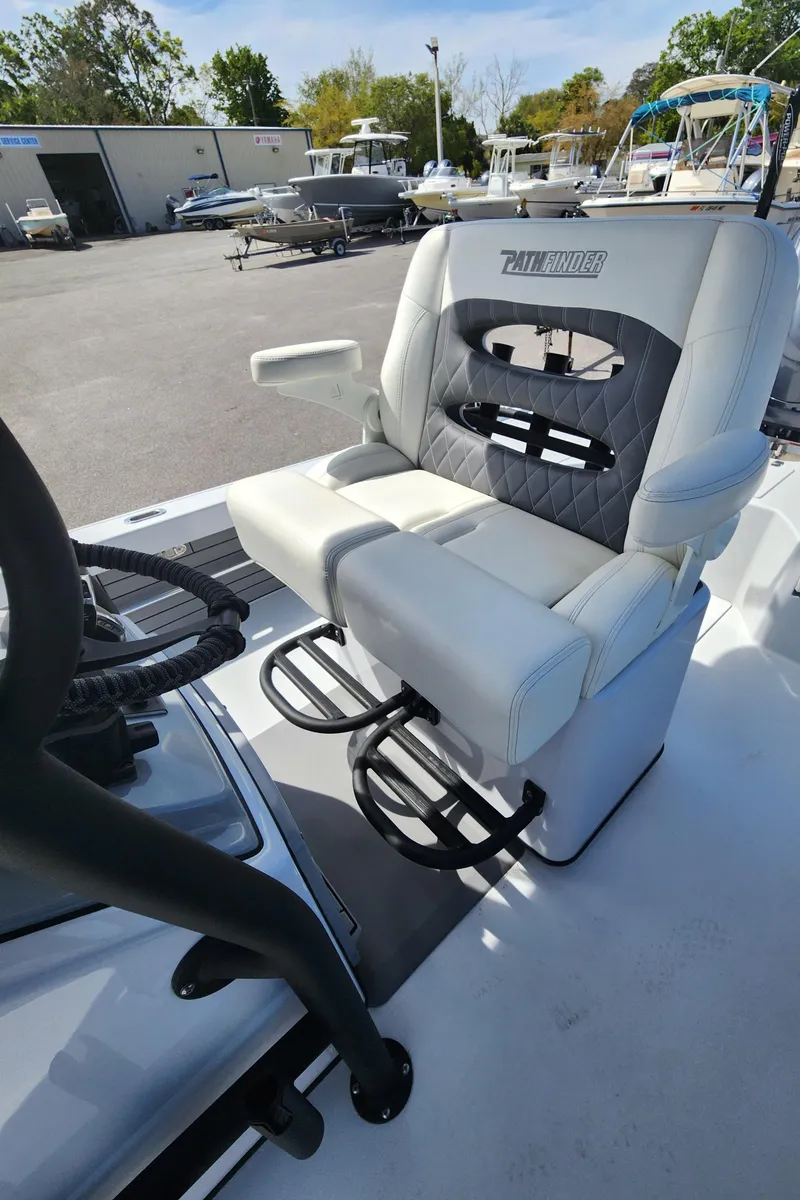 Slide: The Image of 2023 Pathfinder 2500 Hybrid boat seat with white and gray upholstery in a marina setting. - 23