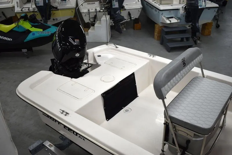 Slide: The Image of 2025 Carolina Skiff E20 JVX Center Console boat in showroom, featuring seating and motor. - 9