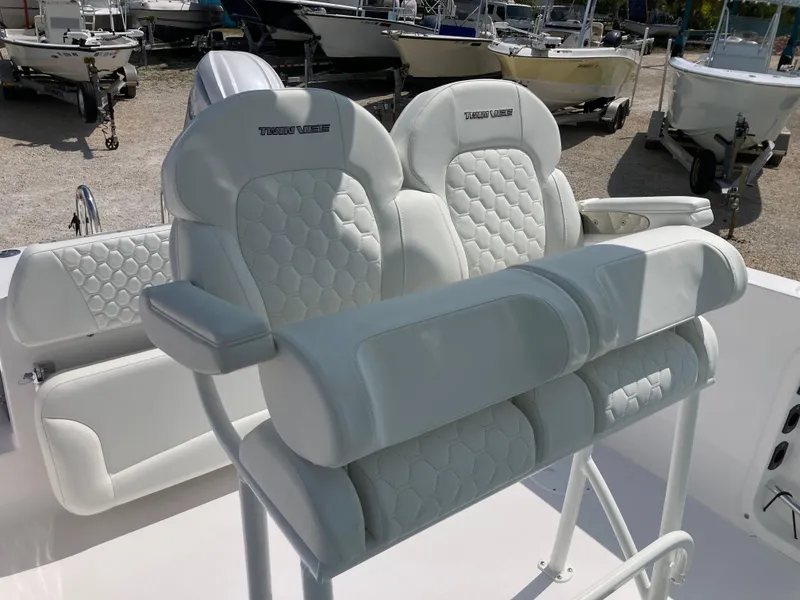 Slide: The Image of 2025 Twin Vee 240GFX boat seats with white quilted upholstery in a marina setting. - 12