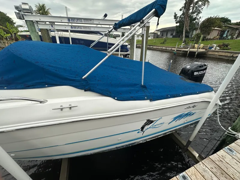 Slide: The Image of 1997 Sea Ray Laguna 21 boat docked with blue cover and Suzuki outboard motor. - 20