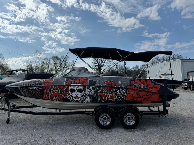 Slide: The Image of 2005 Yamaha Boats 230 SX with vibrant skull and floral artwork, parked on a trailer. - 2