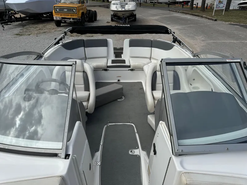 Slide: The Image of 2005 Yamaha Boats 230 SX interior with seating and windshield, parked outdoors. - 6