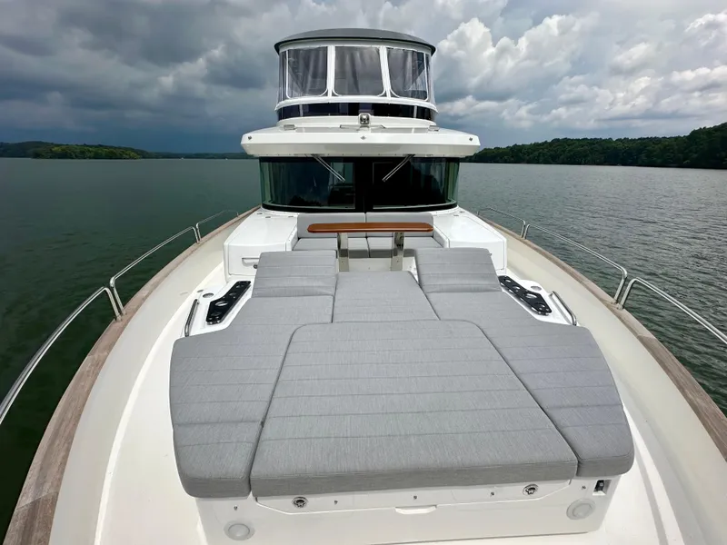Slide: The Image of 2021 Sirena 58 yacht with spacious deck and cushioned seating on a cloudy day. - 11