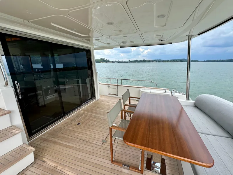 Slide: The Image of Outdoor deck of 2021 Sirena 58 yacht with wooden table and chairs, overlooking serene waters. - 15