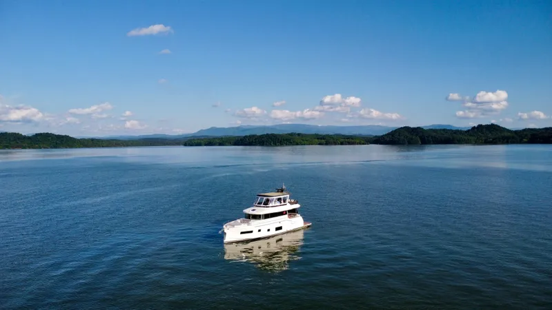 Slide: The Image of A 2021 Sirena 58 yacht cruising on a serene lake under a clear blue sky. - 5