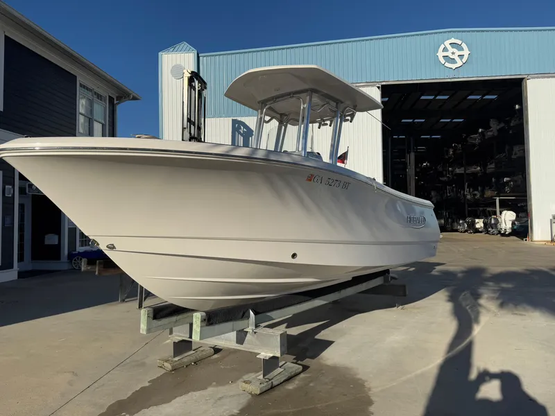 Slide: The Image of 2021 Robalo R230 Center Console boat on display outside a marine warehouse. - 2