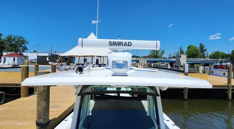 Slide: The Image of 2024 Boston Whaler 330 Outrage with Simrad radar, docked at a marina under clear blue skies. - 10