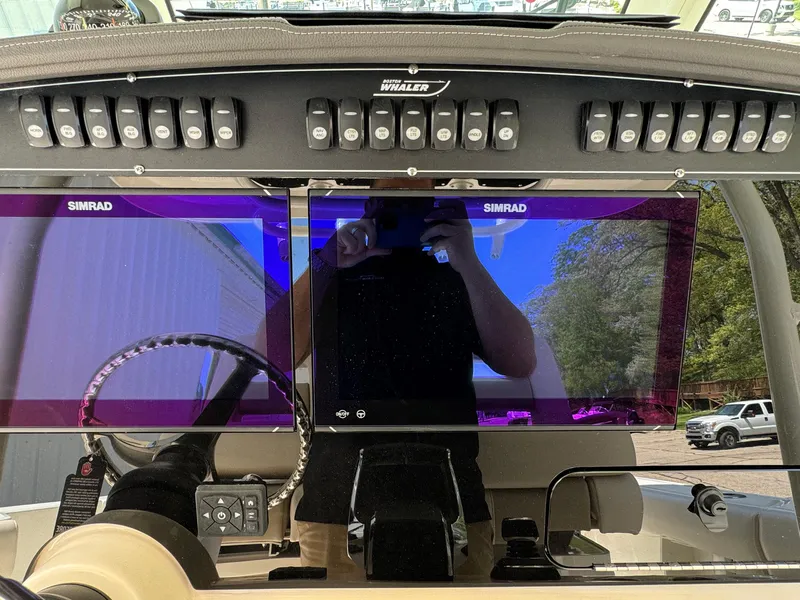 Slide: The Image of 2024 Boston Whaler 330 Outrage dashboard with dual Simrad displays and control panel. - 13
