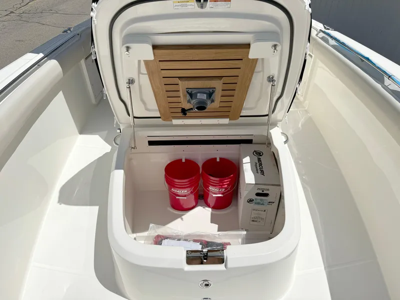 Slide: The Image of 2024 Boston Whaler 330 Outrage storage compartment with red buckets and equipment. - 18
