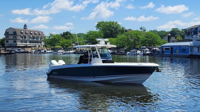 Slide: The Image of 2024 Boston Whaler 330 Outrage boat on a calm lake with scenic background. - 2