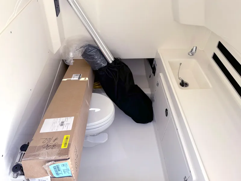 Slide: The Image of 2024 Boston Whaler 330 Outrage interior with sink, toilet, and storage box. - 28