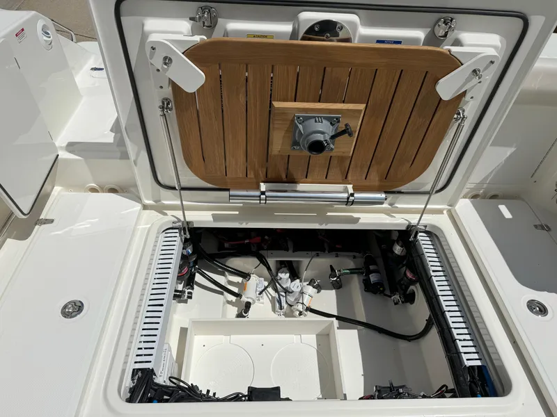 Slide: The Image of 2024 Boston Whaler 330 Outrage boat compartment with open hatch, showcasing internal components. - 31