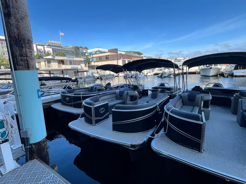 Slide: The Image of 2023 Tahoe Pontoon LTZ Cruise boats docked at a marina under clear blue skies. - 5