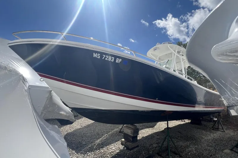Slide: The Image of 2004 Regulator 26FS boat on stands, blue hull, sunny day, white clouds. - 3