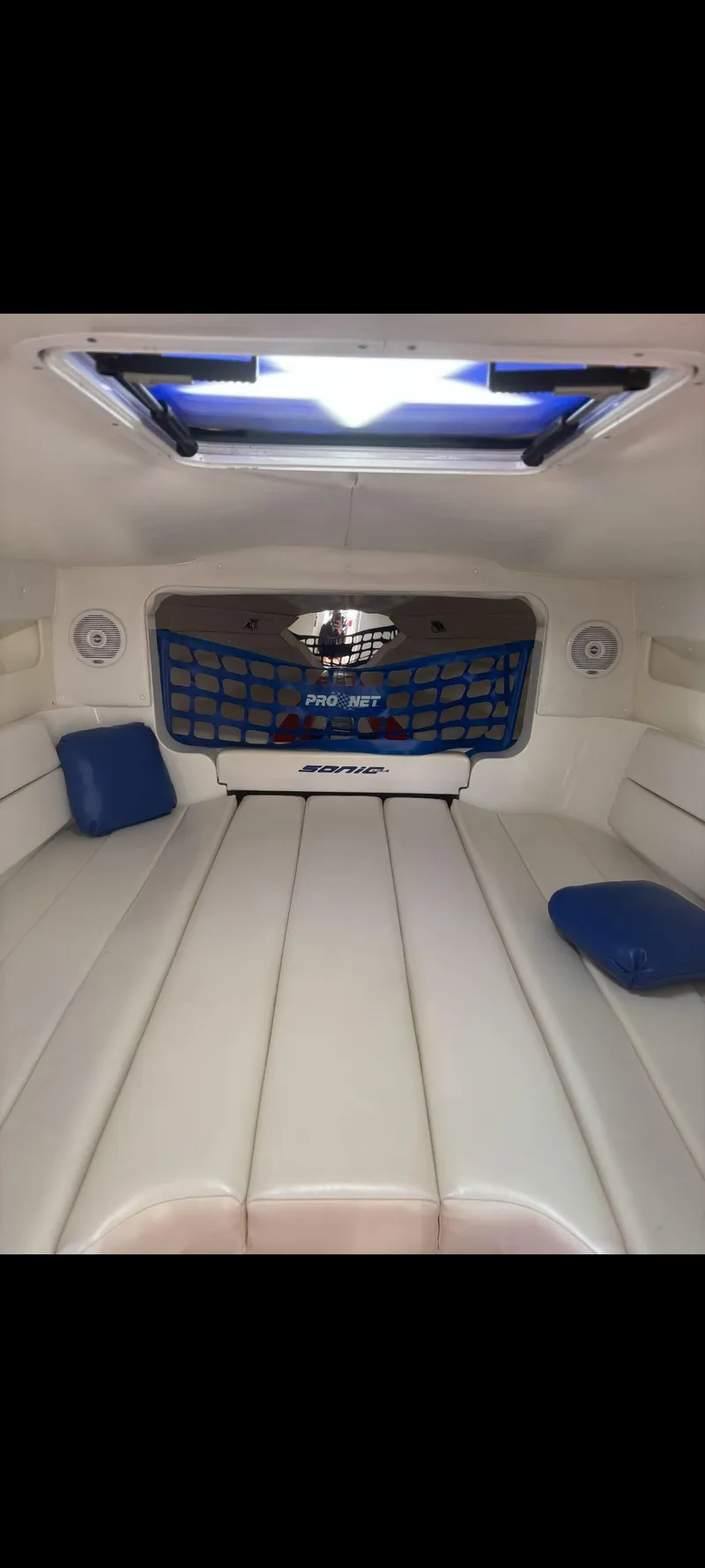 Slide: The Image of Interior of a 2001 Sonic 31 SS boat with white seating and blue accents. - 14