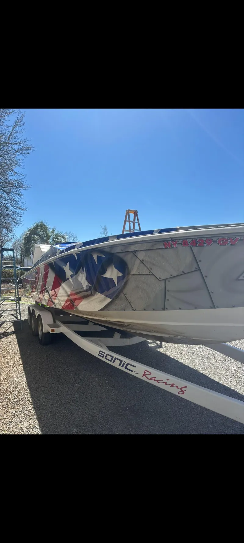 Slide: The Image of 2001 Sonic 31 SS boat with patriotic design on trailer under clear blue sky. - 3