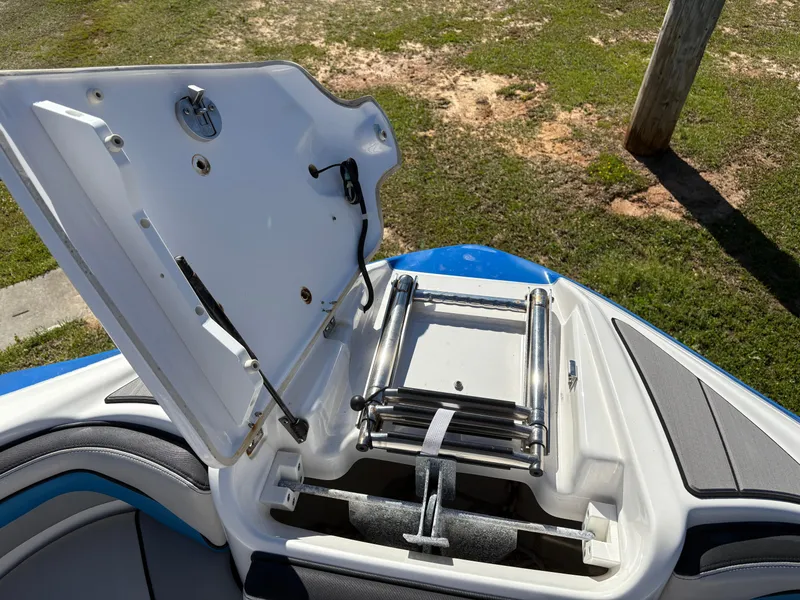 Slide: The Image of Open storage compartment on 2019 Yamaha Boats 242X E-Series, featuring a retractable ladder. - 26