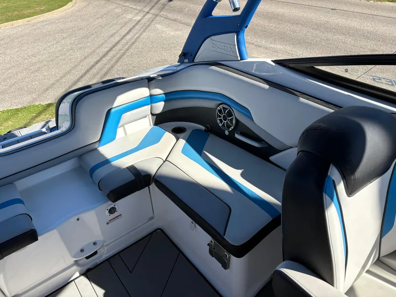 Slide: The Image of 2019 Yamaha Boats 242X E-Series interior with blue and white seating, speaker, and open hatch. - 6