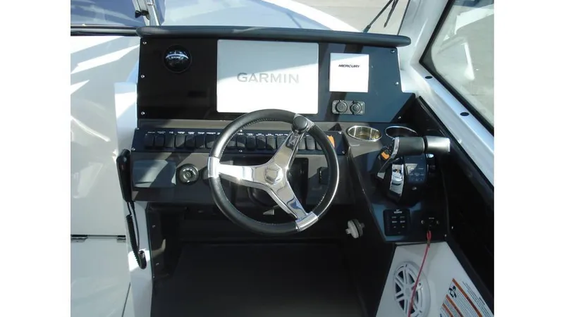 Slide: The Image of 2022 Blackfin 272 DC boat dashboard with Garmin navigation system and steering wheel. - 2