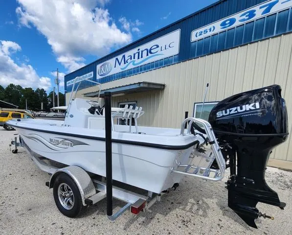 Slide: The Image of 2024 Blue Wave 2000 Classic boat with Suzuki engine at dealership, parked on trailer. - 3