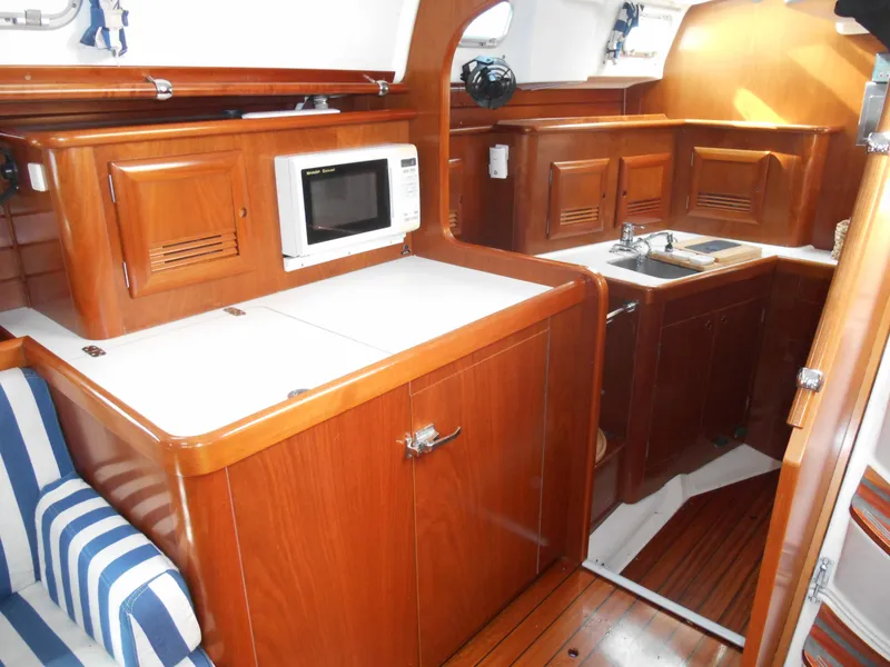 Slide: The Image of Interior of 2000 Beneteau Oceanis 50 yacht with wooden cabinetry and compact kitchen area. - 28