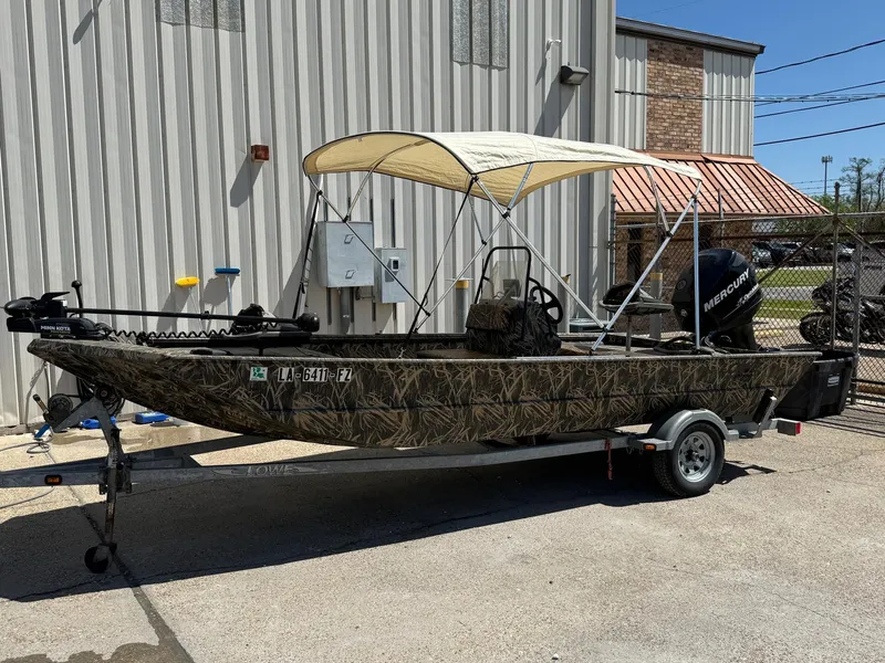 Slide: The Image of 2012 Lowe Roughneck 1860CC boat with canopy on trailer, parked outdoors. - 1