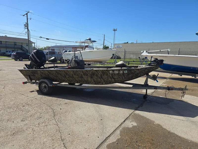 Slide: The Image of 2012 Lowe Roughneck 1860CC boat on trailer, parked outdoors under clear blue sky. - 2