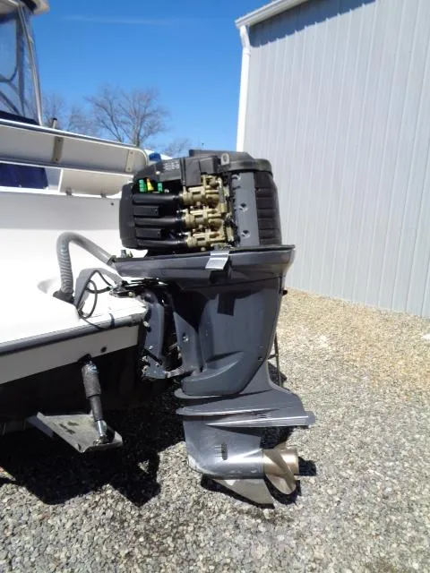 Slide: The Image of 2007 Century 2200 Walkaround boat with outboard motor, parked on gravel near a building. - 23