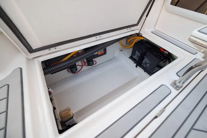 Slide: The Image of Open storage compartment in 2025 Solara S-310 SB boat, showing battery and wiring. - 18